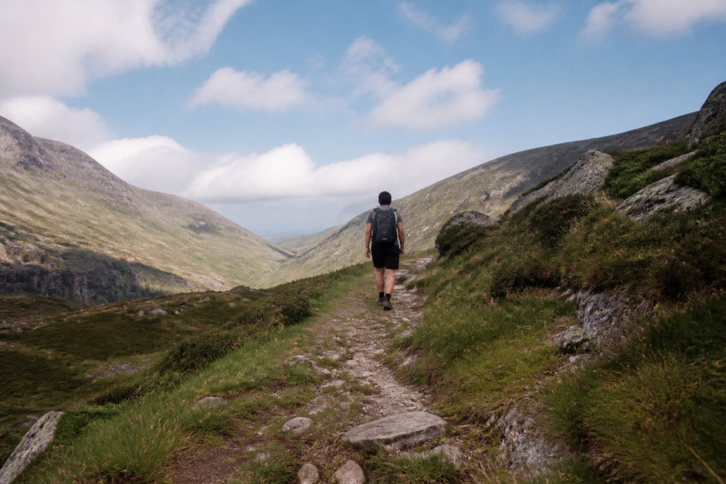 Marcheur solitaire sur sentier herbe montagne ciel